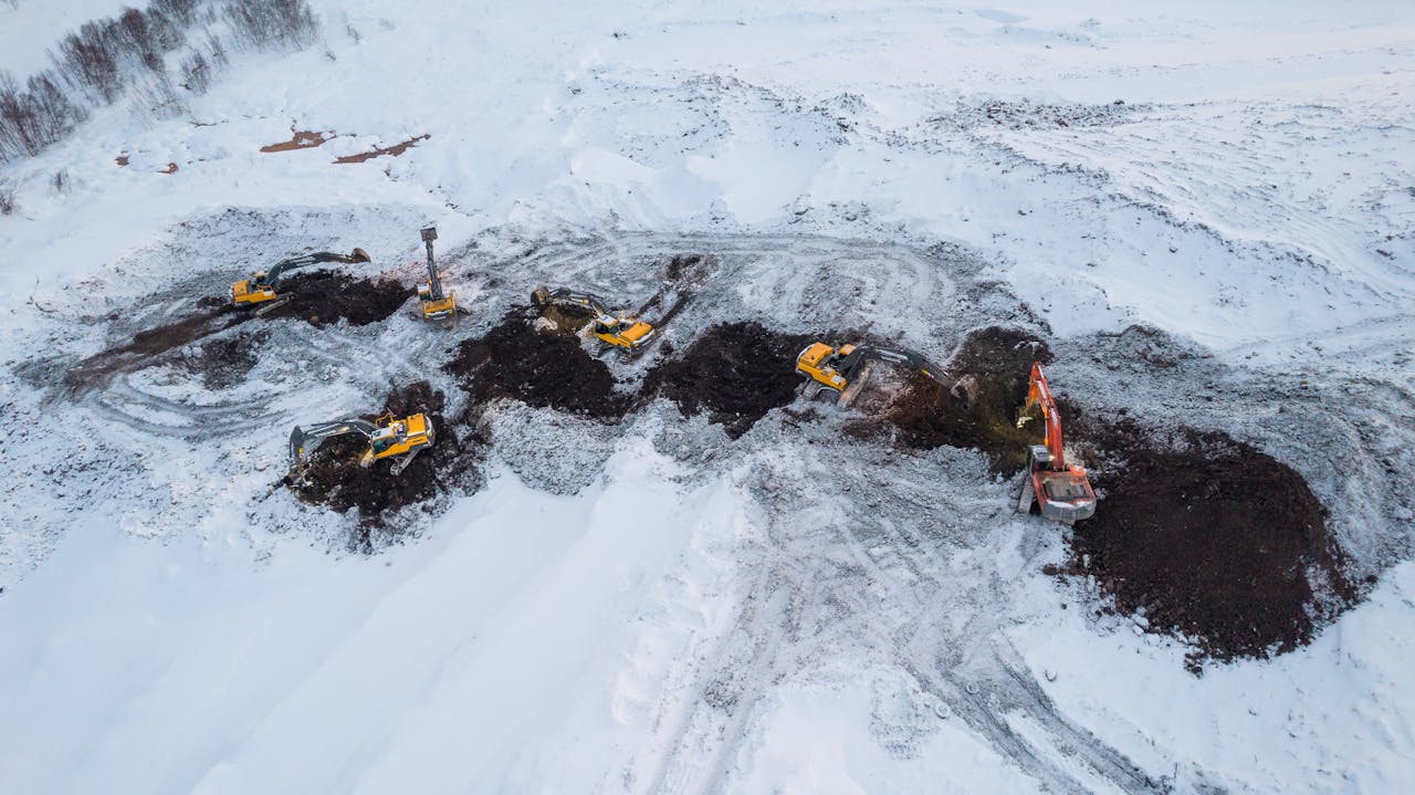 Excavators operating in a snowy landscape in Murmansk, Russia during winter.